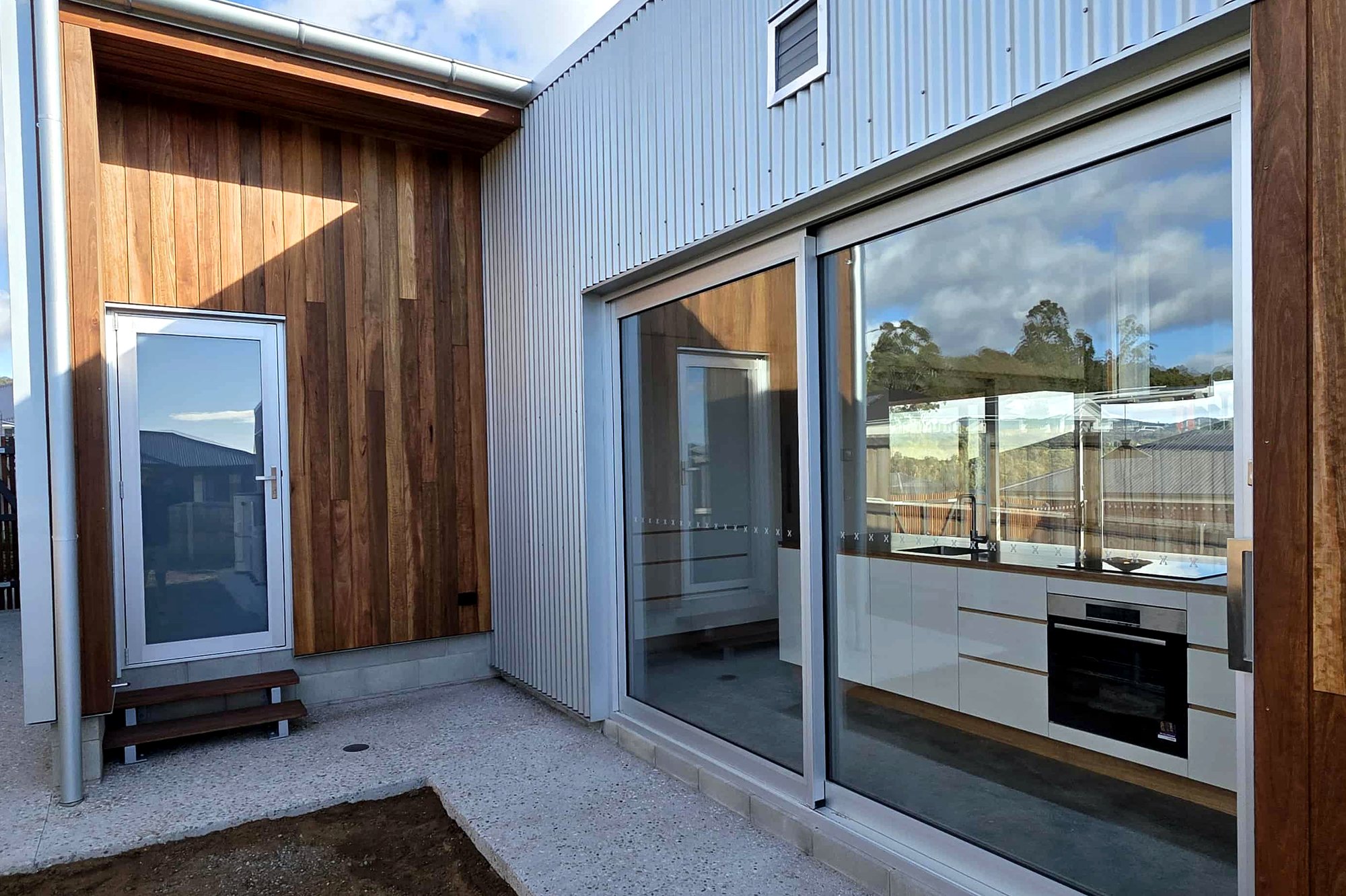 Kingston kitchen seen through sliding doors, timber cladding and corrugated steel exterior