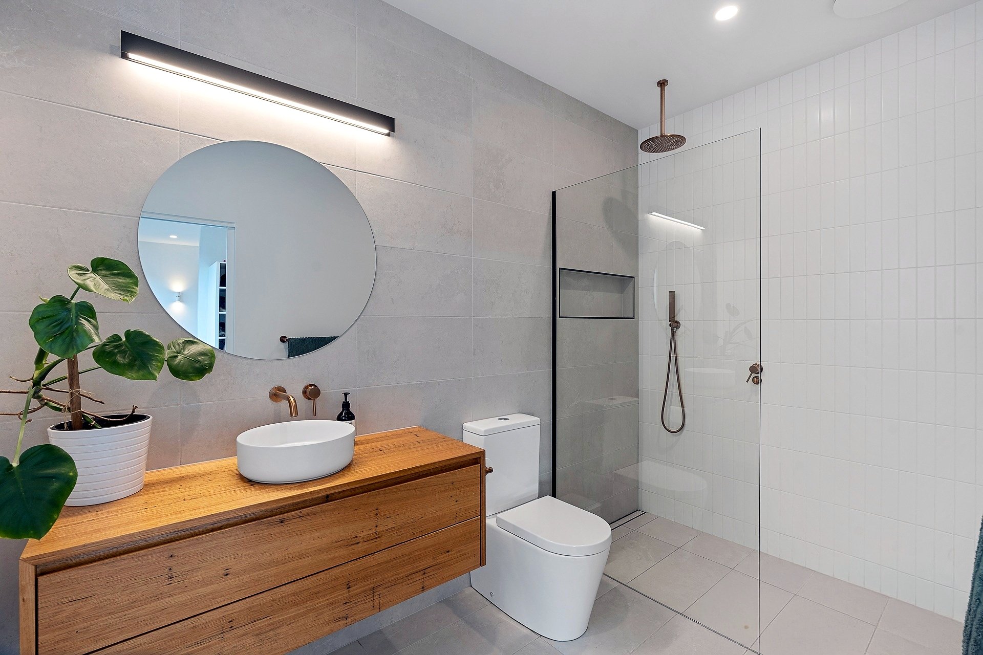 Pardalote bathroom with round mirror, timber vanity, brass tapware and walk-in shower